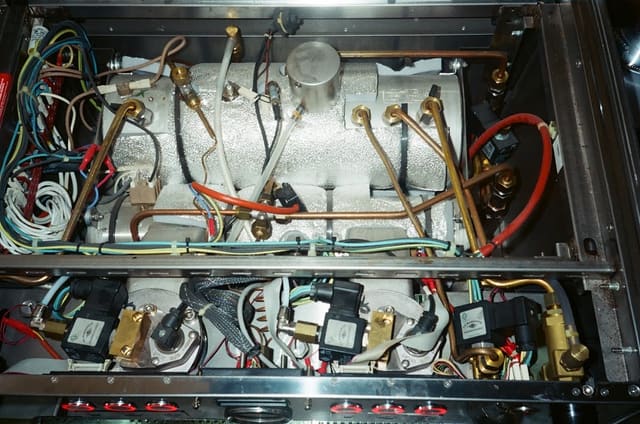 L'intérieur ouvert de la machine à espresso, tuyaux de cuivre et câbles colorés