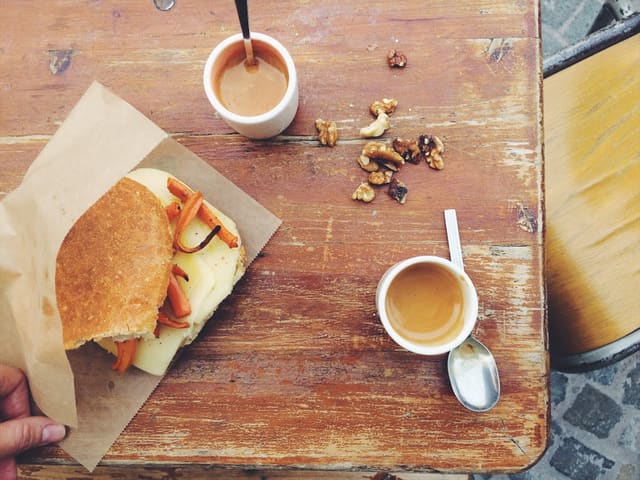Un sandwich et un espresso posés sur une table en bois patinée