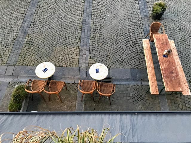 La terrasse vue d'en haut : tables, chaises et banc sur les pavés