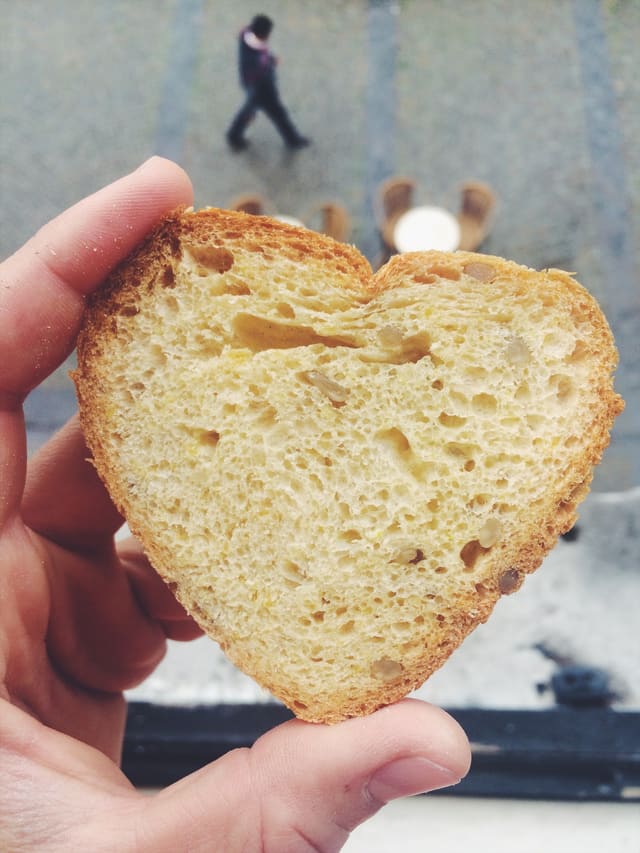 Une tranche de brioche en forme de cœur tenue à la main